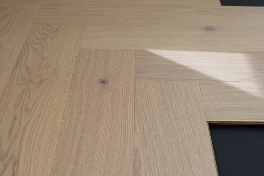 Уложенная паркетная доска «ёлочка» Oak Malta HB у стены - ракурс под углом, видна фактура и швы