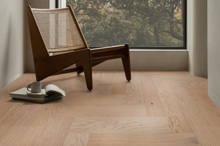 Интерьер с паркетной доской Oak Malta HB у окна — «ёлочка», кресло и обувь у стены, тёплый свет