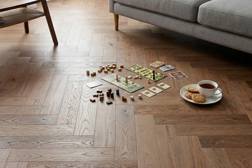 Гостиная: инженерная доска Oak Positano HB «ёлочка», на полу рассыпаны мелкие детали и стоит чашка на блюдце