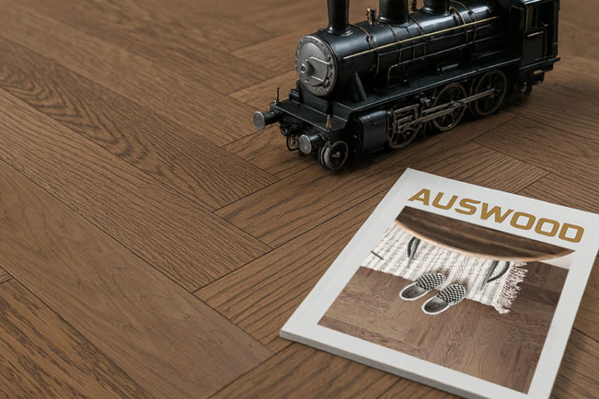 Декор на паркетной доске Oak Positano HB — игрушечный поезд и журнал, крупный план укладки «ёлочка»