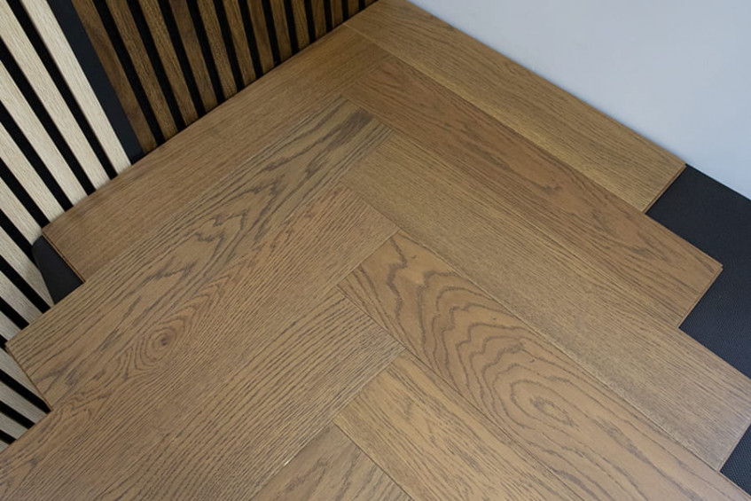 Фрагмент собранной паркетной доски «ёлочки» Oak Positano HB на подложке, ракурс под углом