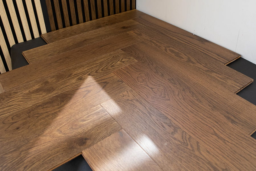 Собранный угол укладки паркетной доски «ёлочка» Oak Rodos HB — тёмный дуб, ракурс под углом, дневной свет